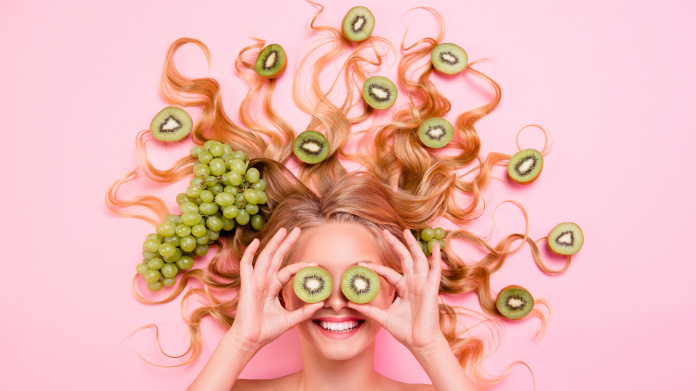 Mulher sorridente com alimentos antioxidantes nos cabelos