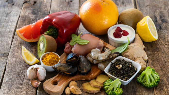 Ostras, ajo, pimiento, yogur, cítricos y otros alimentos sobre una mesa de madera.