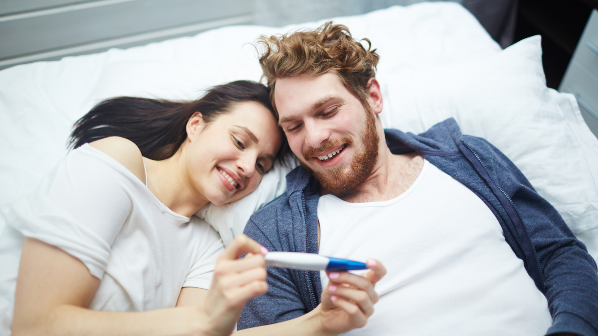Fruchtbares Paar beim Blick auf einen positiven Schwangerschaftstest