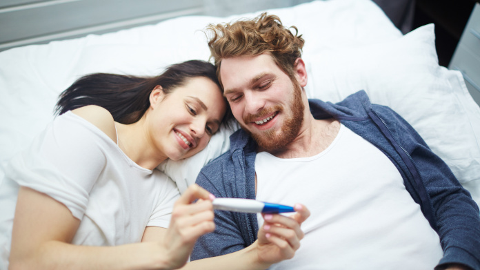 Pareja fértil que mira un test de embarazo positivo