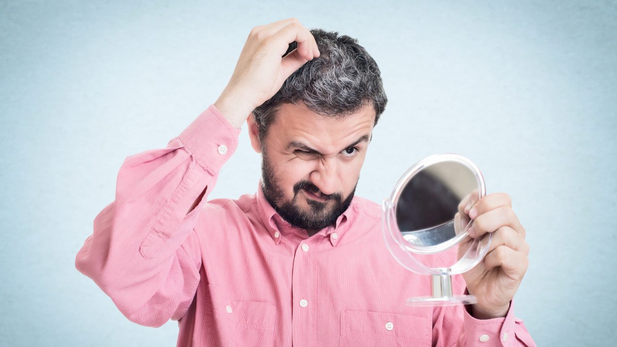 Homme qui voit ses cheveux blanchir dans le miroir