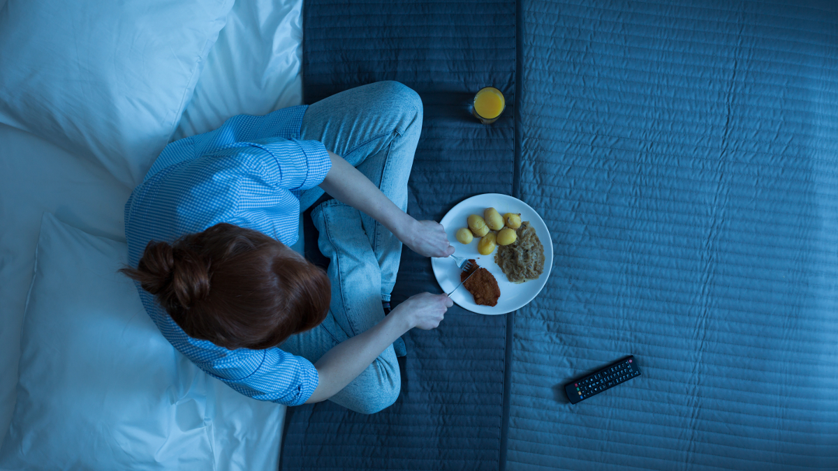 Woman eating at night in bed