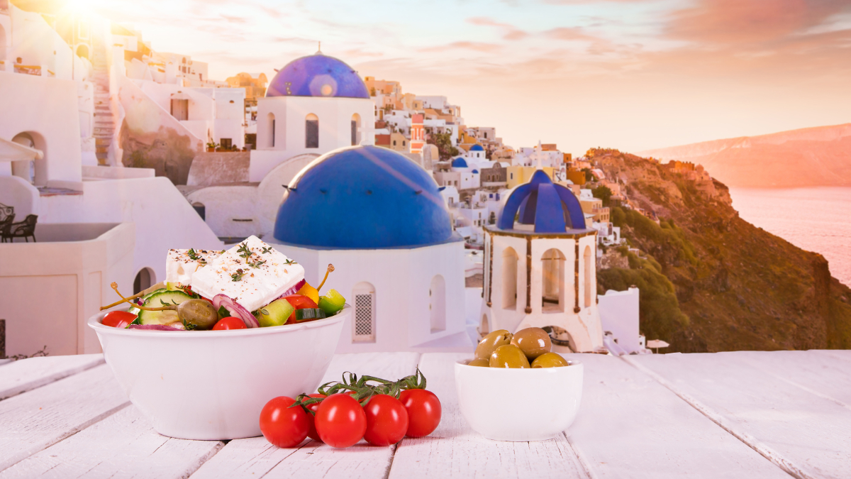 Mediterrane Ernährungsweise mit Tomaten und Oliven vor einer griechischen Landschaft