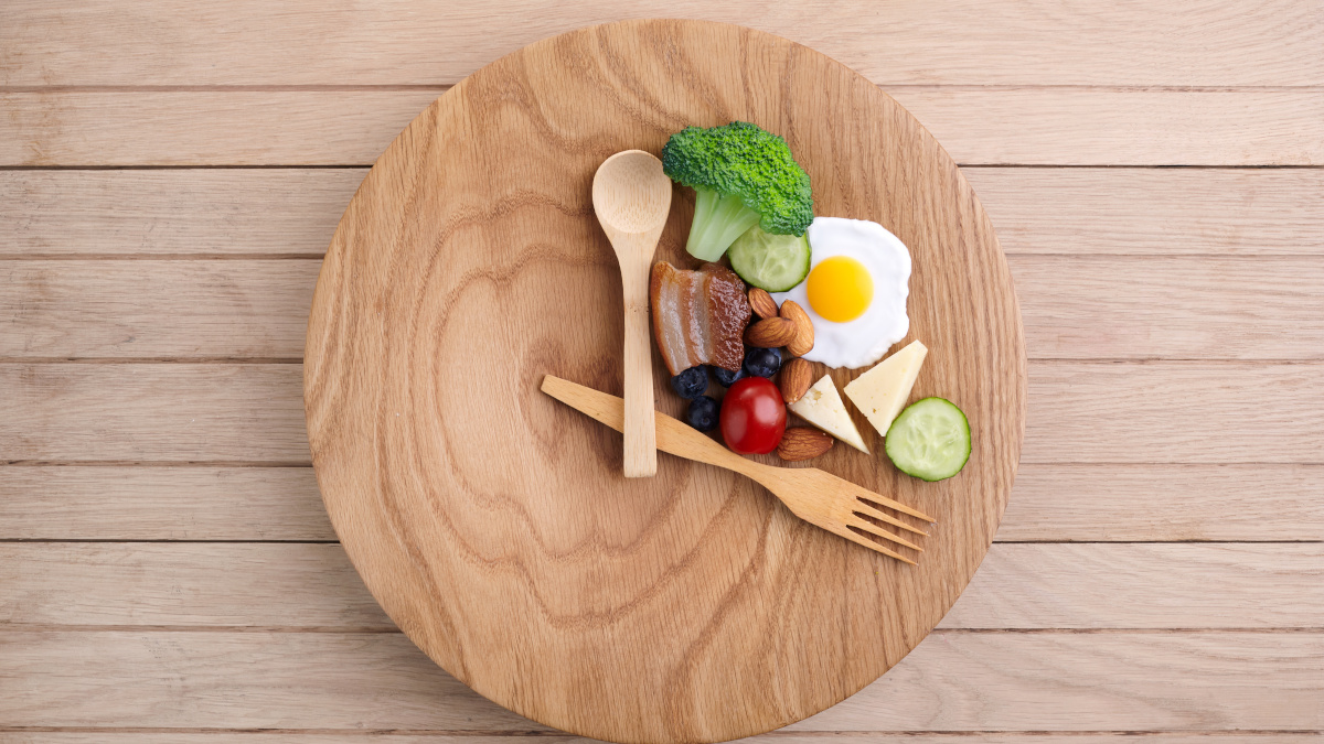 Healthy food with spoon and fork resting on plate symbolizing intermittent fasting